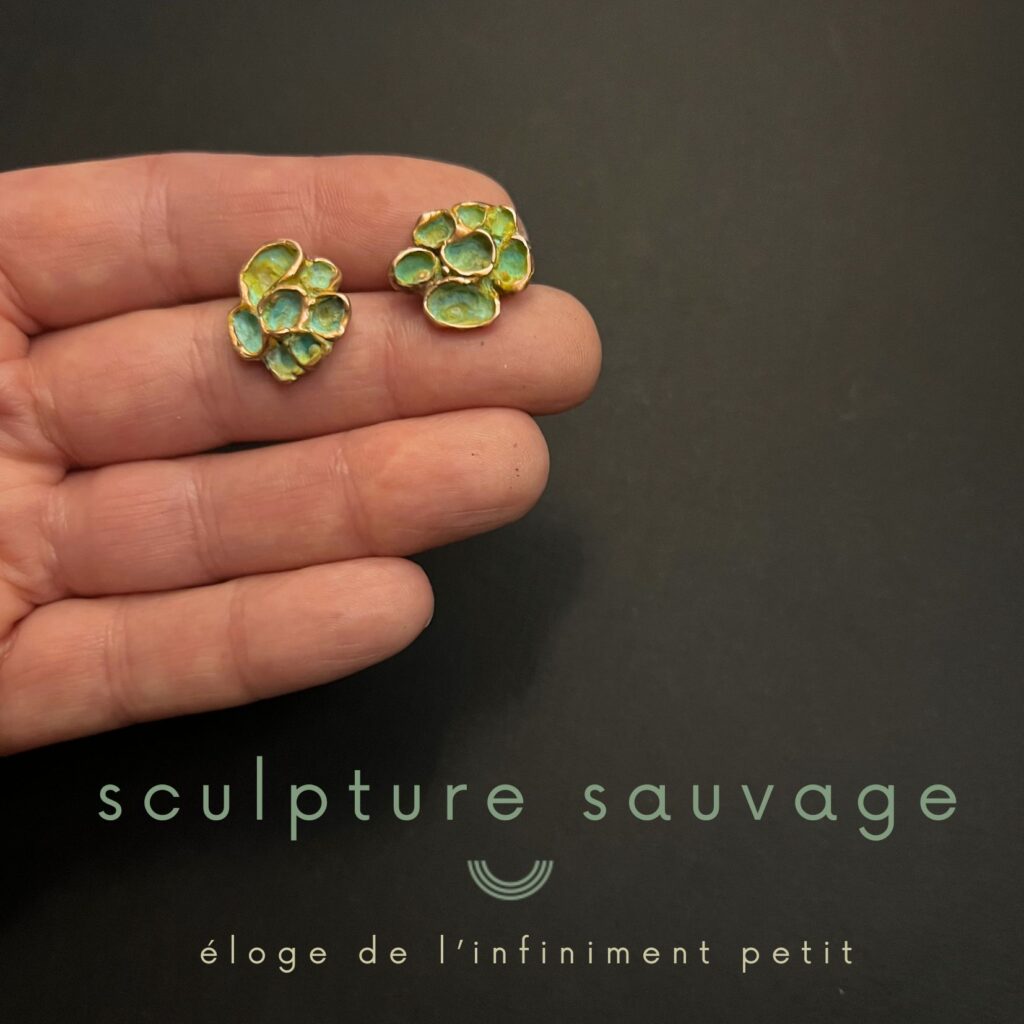 Une main présente une paire de Clous d'oreilles en bronze d'art vert et doré, collection Sculpture sauvage de l'artisane Jane Bosshard Quillerat.